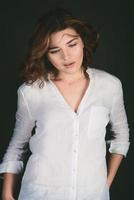 Portrait of young, beautiful sad actress with short brown hair in white shirt and blue pants in the studio photo