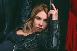 Portrait of the young attractive stylish blonde woman in silk dress and black jacket on the armchair photo