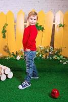 smiling little boy three years old with white puppy of Samoyed on the yellow fence background photo