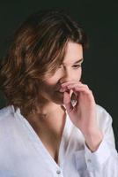 Portrait of young, beautiful sad actress with short brown hair in white shirt and blue pants in the studio photo