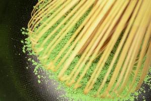 Matcha green tea cooking process in a black bowl with bamboo whisk. Organic green tea matcha powder. Selective focus. photo