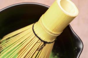 Matcha green tea cooking process in a black bowl with bamboo whisk. Organic green tea matcha powder. Selective focus. photo