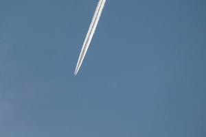 estela blanca de un avión bajo el cielo azul foto