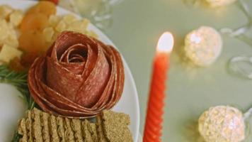 plato de charcutería con salami, diferentes tipos de queso. tiene frutos secos, frutos secos varios y miel. arreglo de vacaciones con velas encendidas video