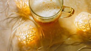 vaso con cerveza fresca y espumosa. en el fondo hay un ambiente romántico con luces video