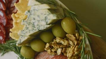 Flat charcuterie with salami, different kinds of cheese. It has dried fruits, various nuts and honey. Holiday arrangement with burning candles
