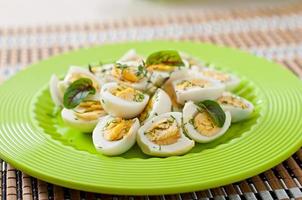 Boiled quail eggs halves on a green plate photo