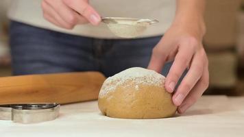 woman hands sprinkle raw dough with a flour, closeup video