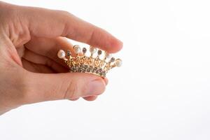 modelo de corona con perlas en la mano