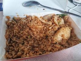 There is still a lot of leftover fried rice in a paper box container. photo