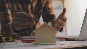 Dos colegas discutiendo el trabajo de datos y una tableta, un portátil con un proyecto arquitectónico en el sitio de construcción en un escritorio en la oficina video