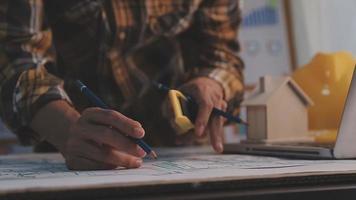 Dos colegas discutiendo el trabajo de datos y una tableta, un portátil con un proyecto arquitectónico en el sitio de construcción en un escritorio en la oficina video