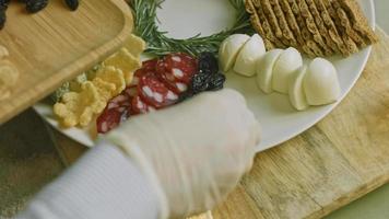 charcutaria plana com salame, diferentes tipos de queijo. tem frutas secas, nozes diversas e mel. arranjo de férias com velas acesas video