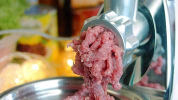 tritare carne con un elettrico carne macinino nel il domestico cucina, selettivo messa a fuoco video