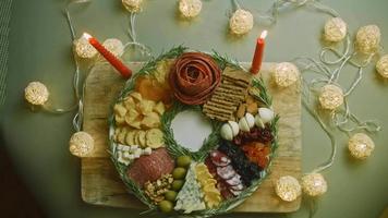 assiette de charcuterie avec salami, différentes sortes de fromages. il contient des fruits secs, diverses noix et du miel. arrangement de vacances avec des bougies allumées video