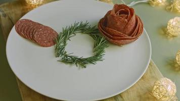 charcutaria plana com salame, diferentes tipos de queijo. tem frutas secas, nozes diversas e mel. arranjo de férias com velas acesas video