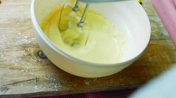 Mix the cake ingredients with the mixer. The baby is sitting in a chair and enjoying himself video