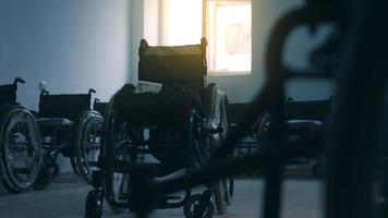 vue latérale d'un ouvrier américain dans un atelier d'une usine de fabrication de fauteuils roulants, assis sur un établi à l'aide d'outils à main et assemblant des pièces d'un produit, assis dans des fauteuils roulants video