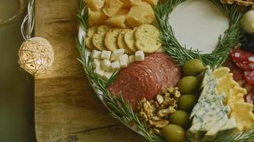 Flat charcuterie with salami, different kinds of cheese. It has dried fruits, various nuts and honey. Holiday arrangement with burning candles video