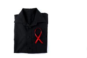 Red ribbon on a black shirt on a white background. Modern treatment and healthcare. AIDS awareness concept. photo