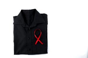 cinta roja en una camisa negra sobre un fondo blanco. tratamiento moderno y cuidado de la salud. concepto de sensibilización sobre el sida. foto