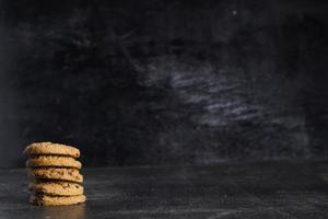 pila de galletas de chocolate en la mesa de madera sobre fondo negro foto