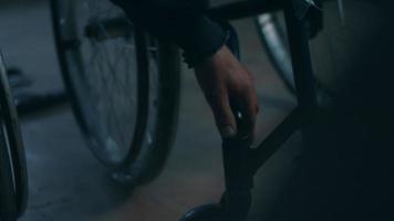 sida se av ett amerikan manlig arbetare i en verkstad på en fabrik framställning rullstolar, Sammanträde på en arbetsbänk använder sig av hand verktyg och montering delar av en produkt, Sammanträde i rullstolar video