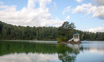 A small beautiful island on Lake Aya in the Altai Territory or the Altai Republic. There is a small gazebo on the island and a forest around the lake. photo