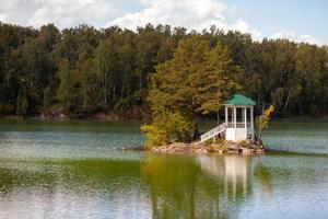 A small beautiful island on Lake Aya in the Altai Territory or the Altai Republic. There is a small gazebo on the island and a forest around the lake. photo
