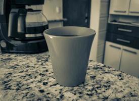 cafetera y taza roja en la mesa de la cocina. foto