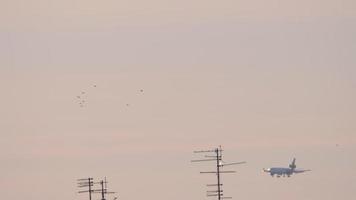 A plane in the distance descends for a landing in sunset light video