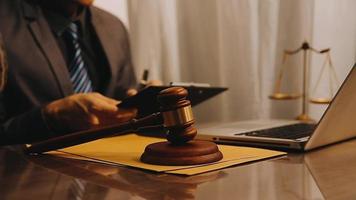 Justice and law concept.Male judge in a courtroom with the gavel, working with, computer and docking keyboard, eyeglasses, on table in morning light video