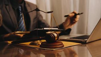 Justice and law concept.Male judge in a courtroom with the gavel, working with, computer and docking keyboard, eyeglasses, on table in morning light video