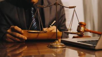 Justice and law concept.Male judge in a courtroom with the gavel, working with, computer and docking keyboard, eyeglasses, on table in morning light video