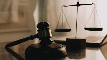 Justice and law concept.Male judge in a courtroom with the gavel, working with, computer and docking keyboard, eyeglasses, on table in morning light video