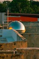 un tanque de agua en el techo con el reflejo de la luz del atardecer foto