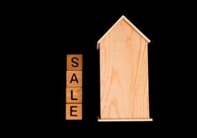 wooden house mockup with house keys, wooden cubes with words rent sale , buy and loan. on black background photo