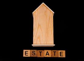 maqueta de casa de madera con llaves de casa, cubos de madera con palabras alquiler venta, compra y préstamo. sobre fondo negro foto