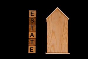 wooden house mockup with house keys, wooden cubes with words rent sale , buy and loan. on black background photo