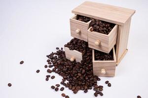 caja de madera con celdas llenas de granos de café. Granos de café dispersos uno al lado del otro aislado sobre fondo blanco. foto