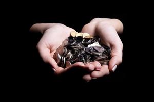 hands holding coins selective and soft focus isolated on black background with copy space. photo