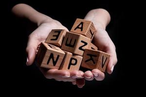 Female hands holds a cube with letters isolated on black photo