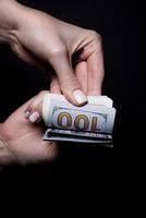 two hands with dollars. Closeup female hand giving money for something with isolated on black background,count, paying, shopping with dollar, corruption, counting dollar banknotes on black photo