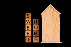 maqueta de casa de madera con llaves de casa, cubos de madera con palabras alquiler venta, compra y préstamo. sobre fondo negro foto