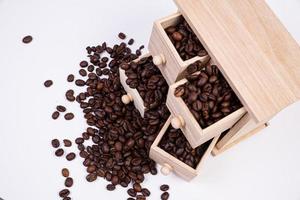 caja de madera con celdas llenas de granos de café. Granos de café dispersos uno al lado del otro aislado sobre fondo blanco. foto