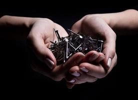 Woman's hands holding screws and dowels in palms. Isolated on black. female hands hold screws nails washers nuts on a black background photo