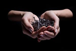 Woman's hands holding screws and dowels in palms. Isolated on black. female hands hold screws nails washers nuts on a black background photo