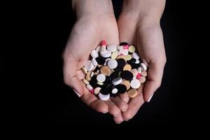 Woman hand holding pill on black background photo