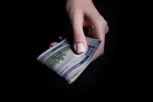 two hands with dollars. Closeup female hand giving money for something with isolated on black background,count, paying, shopping with dollar, corruption, counting dollar banknotes on black photo