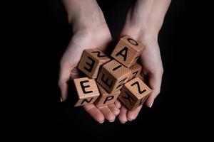 las manos femeninas sostienen un cubo con letras aisladas en negro foto